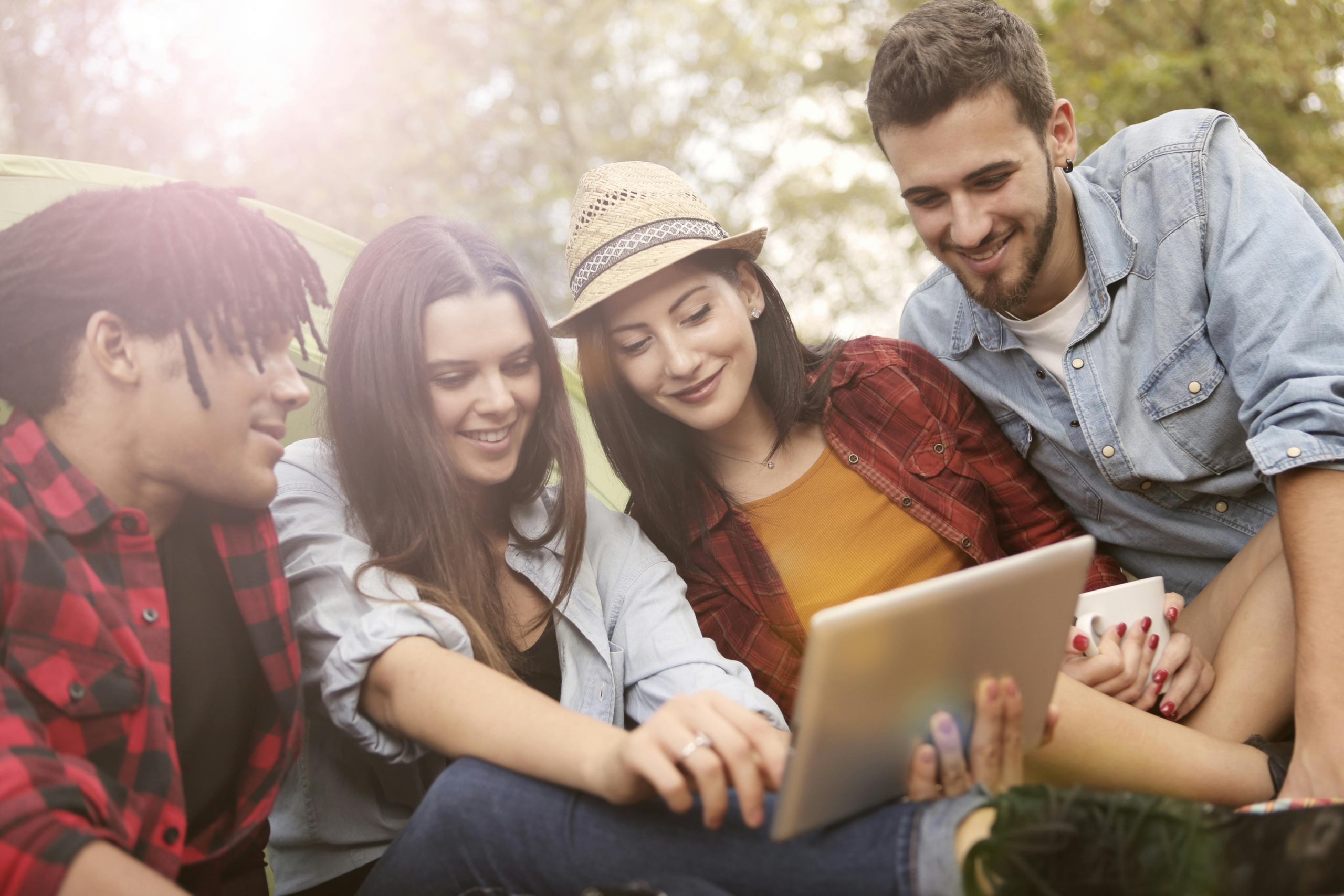 Vier Studierende, die auf ein Tablet schauen