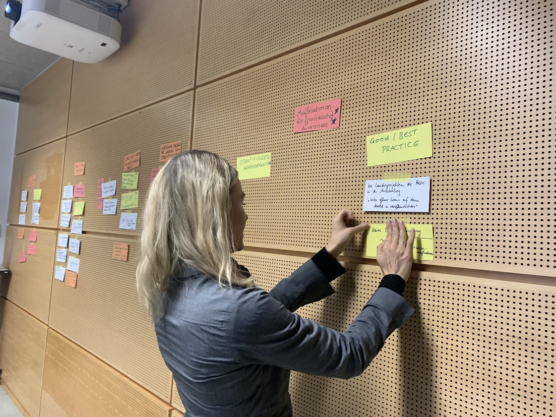 Noreen Krause klebt Post-it an die Wand.